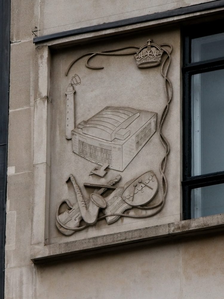 One of three plaques celebrating the 1951 Festival of Britain on the side of Zara just east of Oxford Circus. This one depicts the Royal Festival Hall, which had just been built.