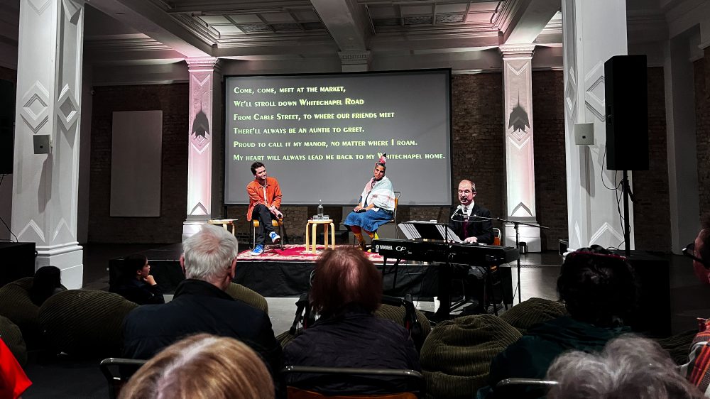 Aya Haidar, centre stage, watching Tom Carradine play and sing the premier performance of Love Song for Whitechapel